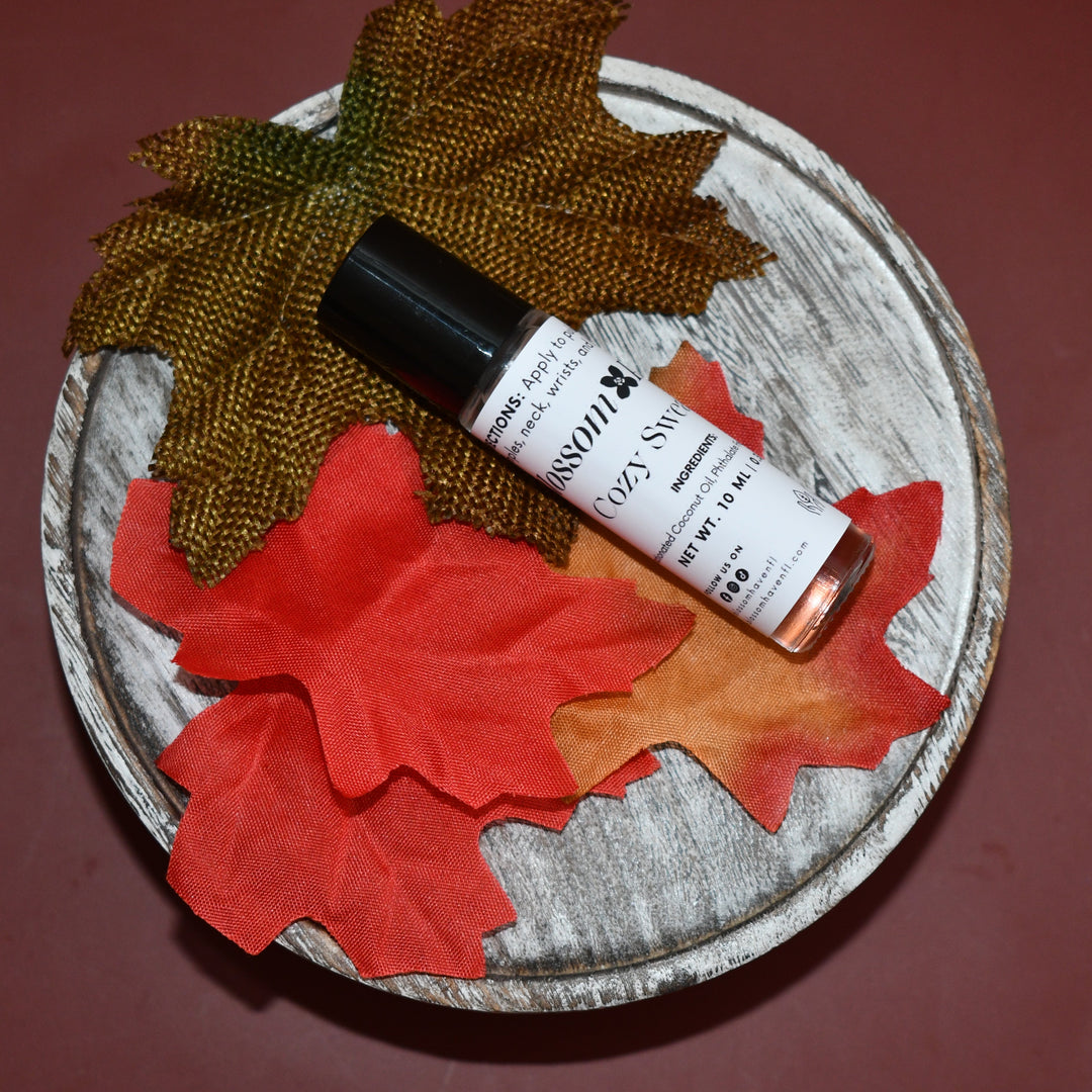 Small bottle of perfume on a round wooden coaster with autumn leaves