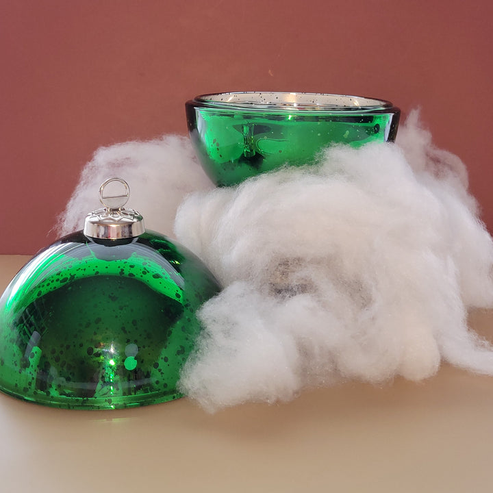 Green glass ornament with cotton on a pink background