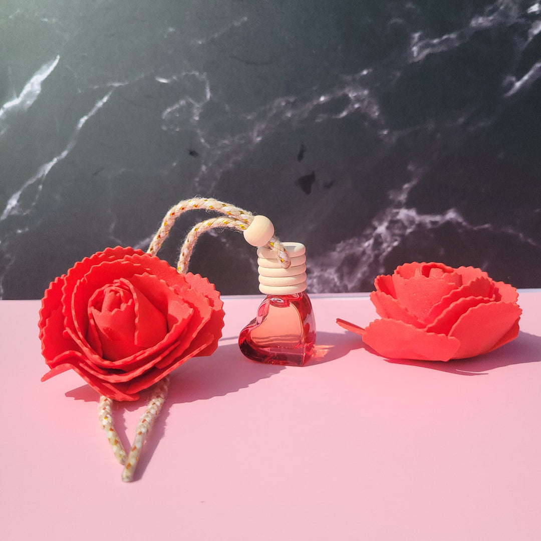 Perfume bottle with red floral design on a pink and black marble surface