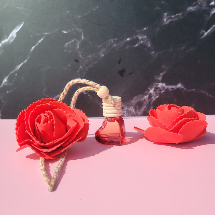 Perfume bottle with red floral design on a pink and black marble surface