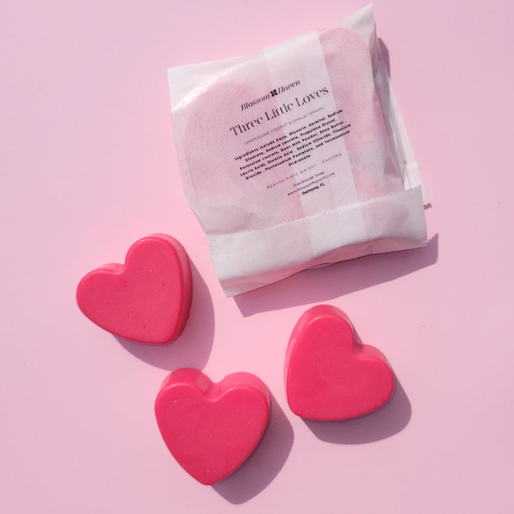 Pink heart-shaped mini soaps and a white package on a pink background