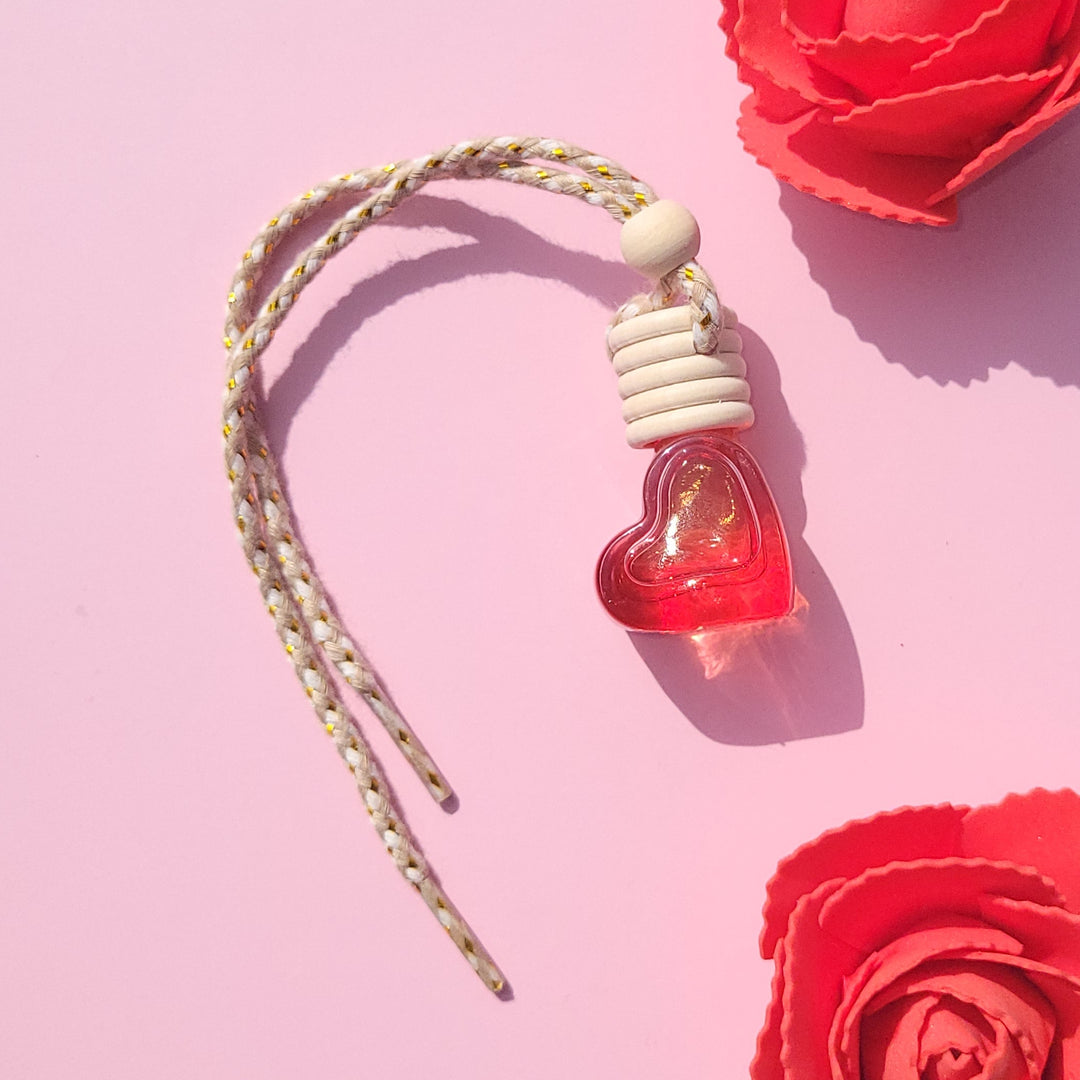 Red heart shaped car diffuser on a pink background.