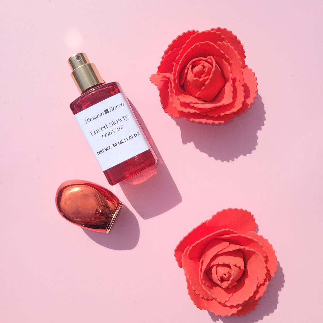 Perfume bottle with red flowers on a pink background