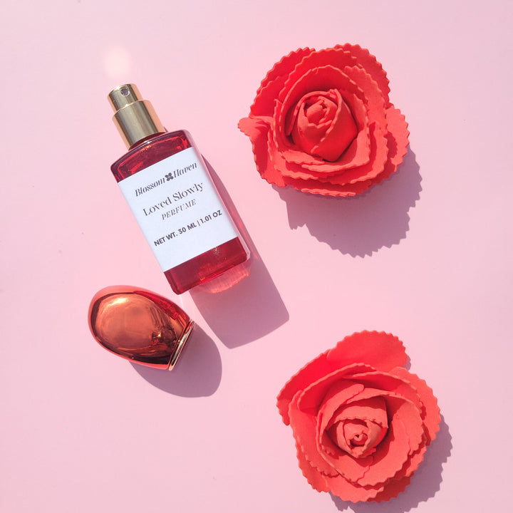 Perfume bottle with red flowers on a pink background