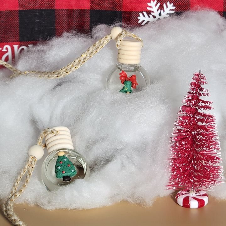 Christmas-themed earbud covers with tree and snowflake designs on a red and black checkered fabric background.